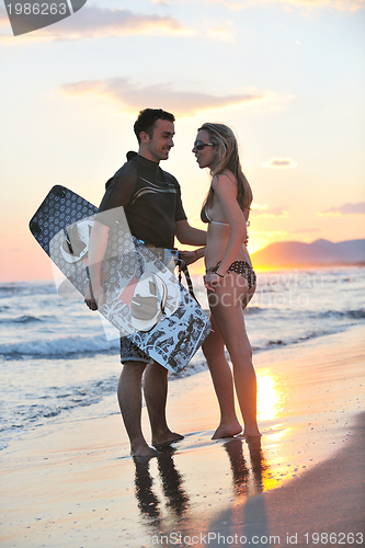 Image of surf couple posing at beach on sunset