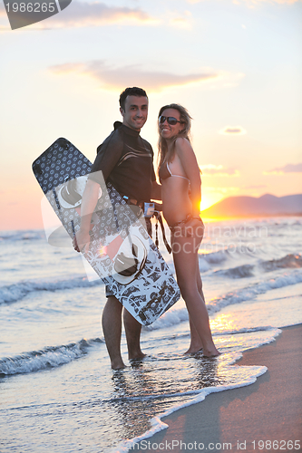 Image of surf couple posing at beach on sunset