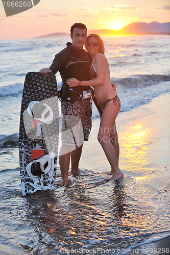 Image of surf couple posing at beach on sunset