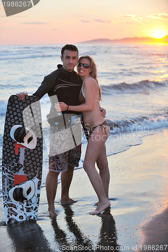 Image of surf couple posing at beach on sunset