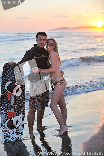 Image of surf couple posing at beach on sunset