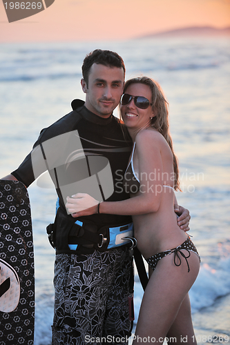 Image of surf couple posing at beach on sunset