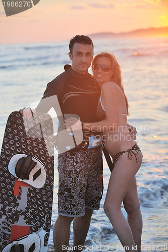 Image of surf couple posing at beach on sunset