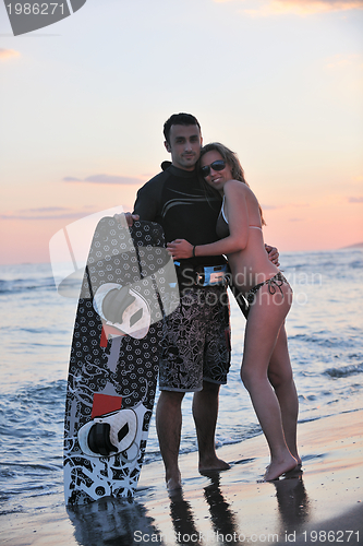 Image of surf couple posing at beach on sunset