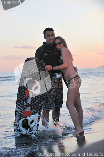 Image of surf couple posing at beach on sunset