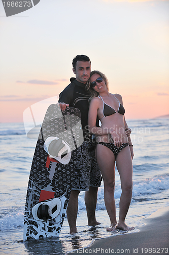 Image of surf couple posing at beach on sunset