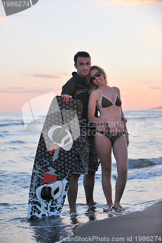 Image of surf couple posing at beach on sunset