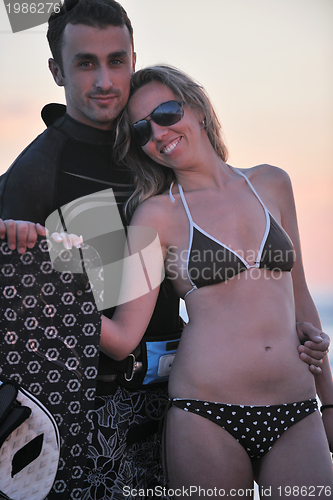 Image of surf couple posing at beach on sunset