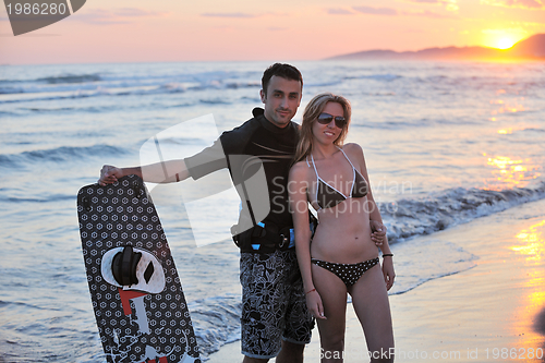 Image of surf couple posing at beach on sunset