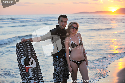 Image of surf couple posing at beach on sunset