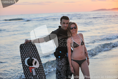 Image of surf couple posing at beach on sunset