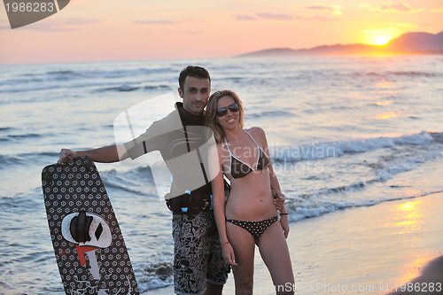 Image of surf couple posing at beach on sunset