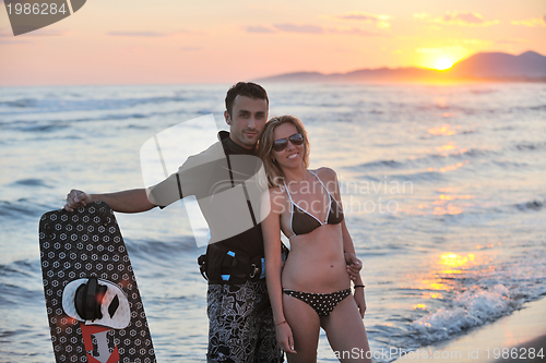 Image of surf couple posing at beach on sunset