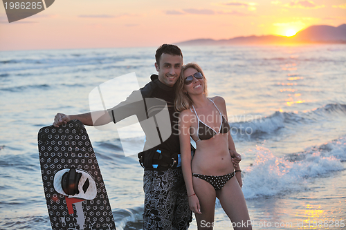 Image of surf couple posing at beach on sunset