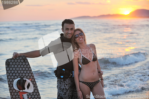Image of surf couple posing at beach on sunset