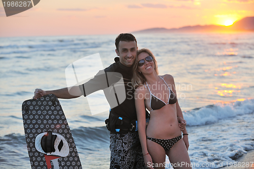 Image of surf couple posing at beach on sunset