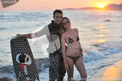 Image of surf couple posing at beach on sunset