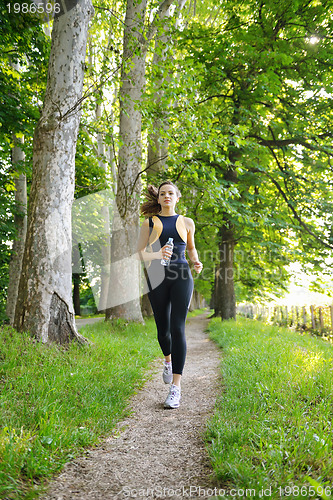Image of Young beautiful  woman jogging at morning in park