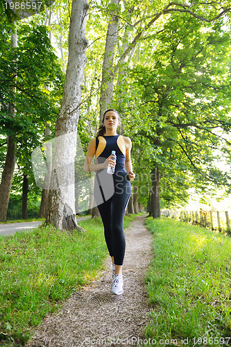 Image of Young beautiful  woman jogging at morning in park