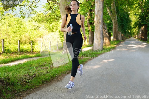 Image of Young beautiful  woman jogging at morning in park