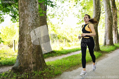 Image of Young beautiful  woman jogging at morning in park