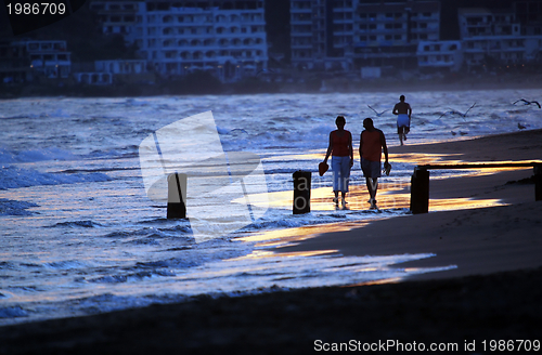 Image of romantic couple walking on beach at sunset