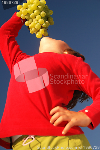 Image of happy girl with grape outside