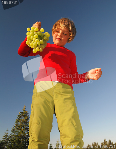 Image of happy girl with grape outside