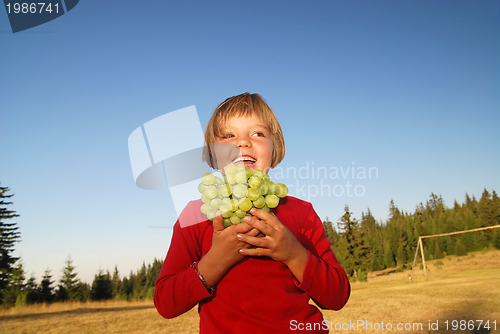 Image of happy girl with grape outside