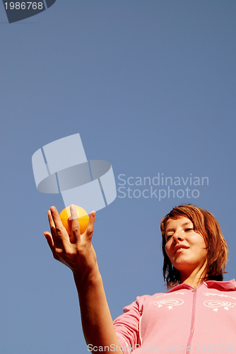 Image of beautyful girl throwing orange in air