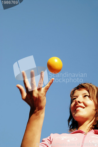 Image of beautyful girl throwing orange in air
