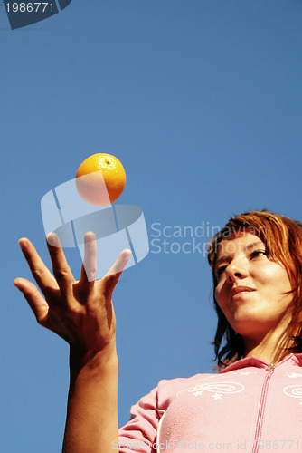 Image of beautyful girl throwing orange in air