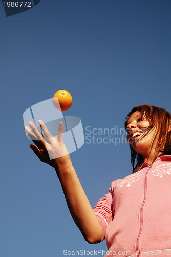 Image of beautyful girl throwing orange in air