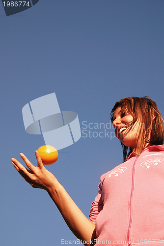 Image of beautyful girl throwing orange in air