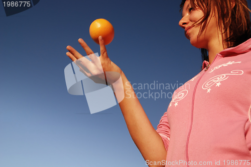 Image of beautyful girl throwing orange in air