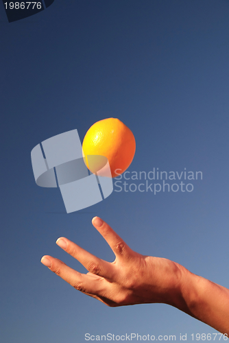 Image of female hand balancing iorange in air