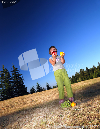 Image of happy girl throwing apple outside