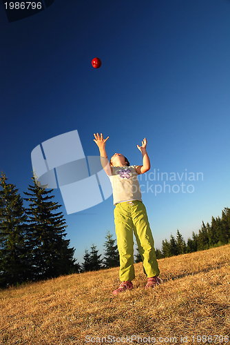 Image of happy girl throwing apple outside