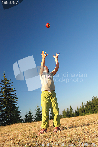 Image of happy girl throwing apple outside