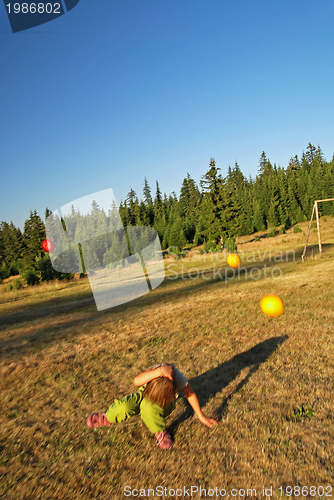 Image of happy girl throwing apple outside
