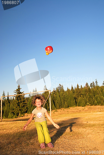 Image of happy girl throwing apple outside