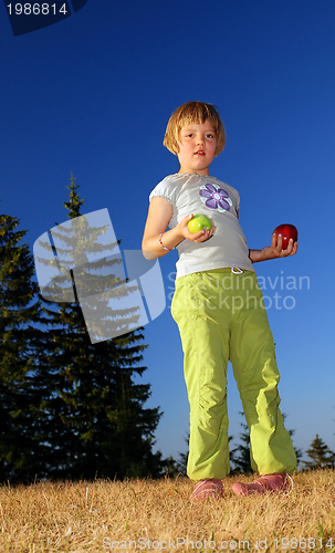 Image of happy girl throwing apple outside
