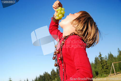 Image of happy girl with grape outside
