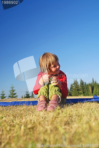 Image of cute little girl eating healthy food outdoor