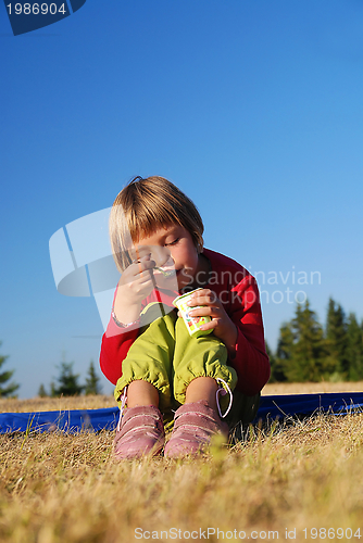 Image of cute little girl eating healthy food outdoor