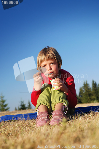 Image of cute little girl eating healthy food outdoor