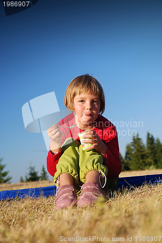 Image of cute little girl eating healthy food outdoor