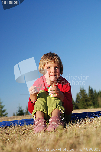 Image of cute little girl eating healthy food outdoor