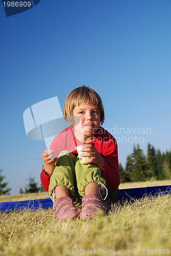 Image of cute little girl eating healthy food outdoor