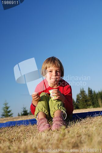 Image of cute little girl eating healthy food outdoor